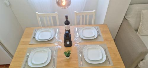 a wooden table with white plates and wine glasses at Vivienda vacacional a 10 minutos de la capital. in Arucas