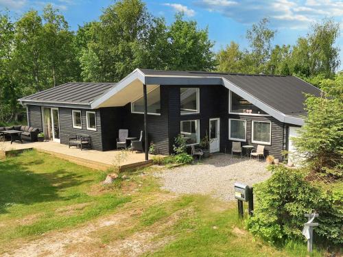 a black house with a porch and a patio at 8 person holiday home in Storvorde in Storvorde