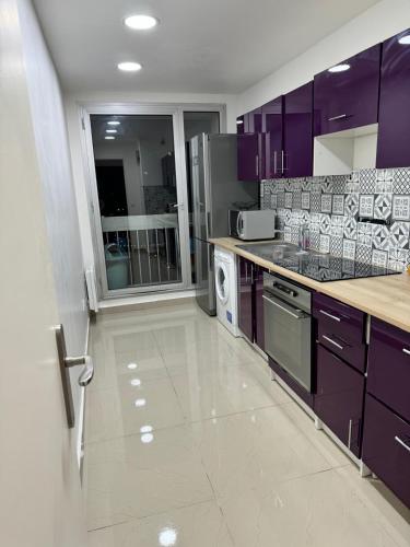 - une cuisine avec des placards violets et un four avec plaques de cuisson dans l'établissement Appartement - La Défense, à Puteaux