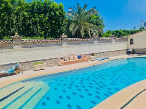 a large swimming pool next to a retaining wall at فيلا كينج مريوط in King Mariout