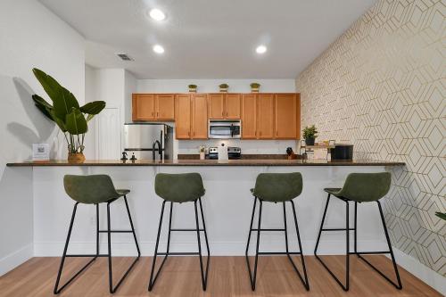 a kitchen with green bar stools at a counter at Trendy Retreat - Great Location - Fully Loaded in Kissimmee
