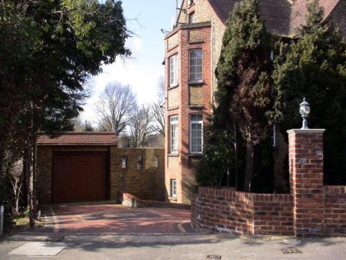 a large brick house with a garage in front of it at The Bridge House in Hounslow
