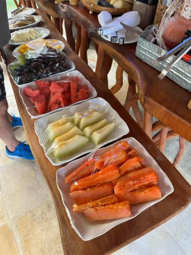 a table with several trays of different types of food at Nauru Chalés Milagres in São Miguel dos Milagres