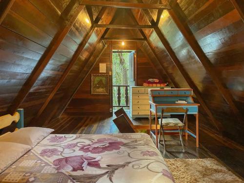 um quarto com uma cama e uma secretária num sótão em Chalé Floresta Amada em Ouro Preto