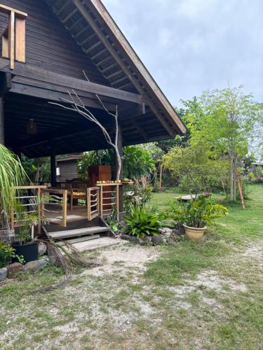 una casa con porche y algunas plantas en el patio en Great House BY Manaeva Lodge en Temae