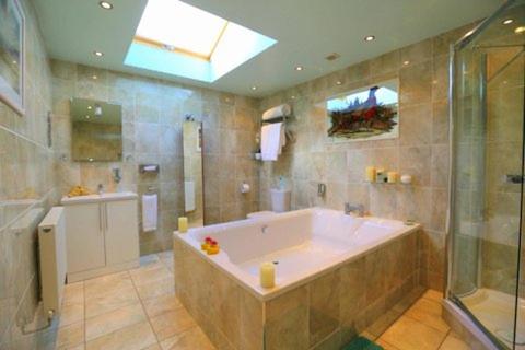 een grote badkamer met een groot bad en een douche bij Pheasant Suites in Colchester