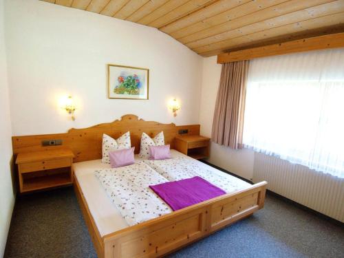 een slaapkamer met een groot houten bed met paarse kussens bij Kirschbaum 3 in Ehrwald