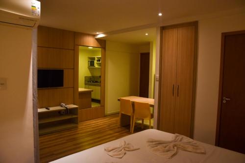 Cette chambre comprend un lit, une table et un bureau. dans l'établissement Studio Moderno bem localizado, à Feira de Santana