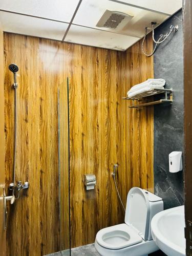 a bathroom with a wooden wall with a toilet and a sink at شقق الريم الجديد للشقق المخدومة Al Reem Al Jadid residence in Yanbu