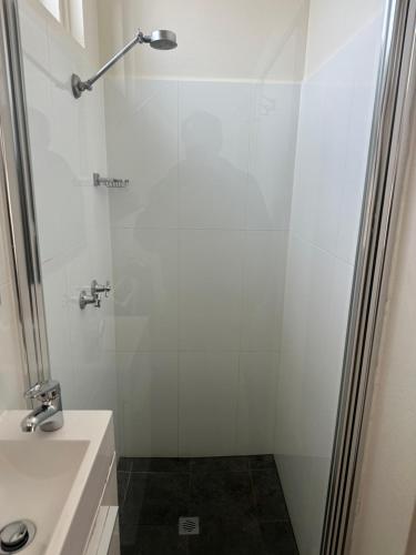 baño blanco con ducha y lavamanos en Memphis Motor Inn, en Parkes