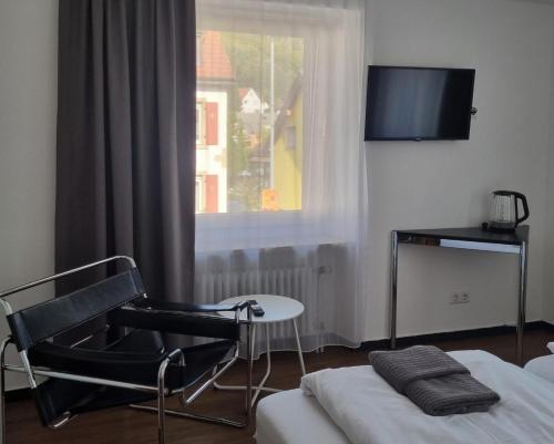 een kamer met een stoel, een tv en een raam bij Am Basler Tor in Grenzach-Wyhlen