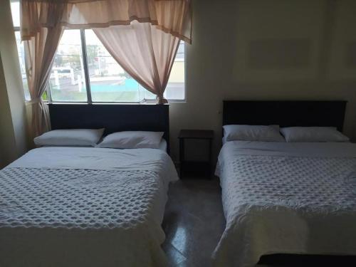 2 camas num quarto com uma janela em Hotel Noche Bella em Ipiales