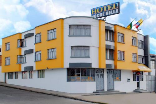 um hotel amarelo e branco com um sinal em Hotel Noche Bella em Ipiales