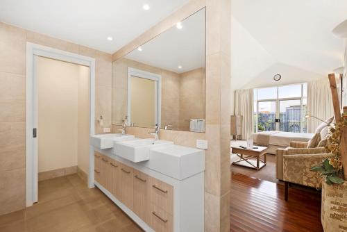 a bathroom with two sinks and a living room at Captain's at the Bay in Apollo Bay