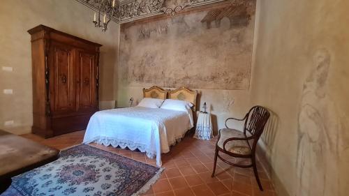 a bedroom with a bed and a chair at Palazzo Pirro Dimora Storica in Acciano