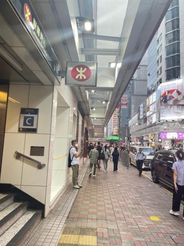 a group of people walking down a city street at 铜锣湾近地铁巴士交通便利宽敞舒适自助入住 in Hong Kong