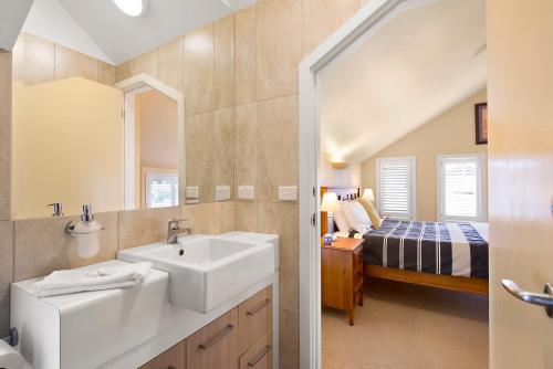a bathroom with a sink and a bedroom with a bed at Captain's at the Bay in Apollo Bay