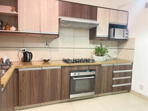 a kitchen with wooden cabinets and a stove at 3-Bedroom Condo in a Golf Course in Santa Cruz de la Sierra