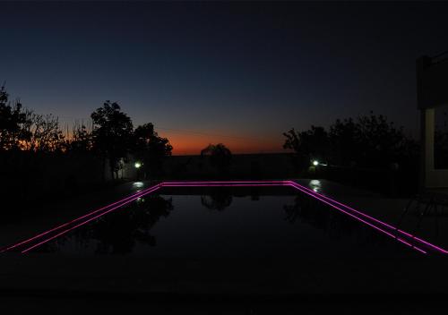 a swimming pool with purple lights in the dark at Vila Haja - Beautiful Farmhouse with a Private Pool! in Imouzzer Kandar
