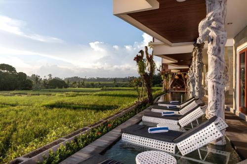 - une rangée de chaises longues sur la terrasse couverte d'une maison dans l'établissement Wadari Retreat Villa Ubud, à Ubud