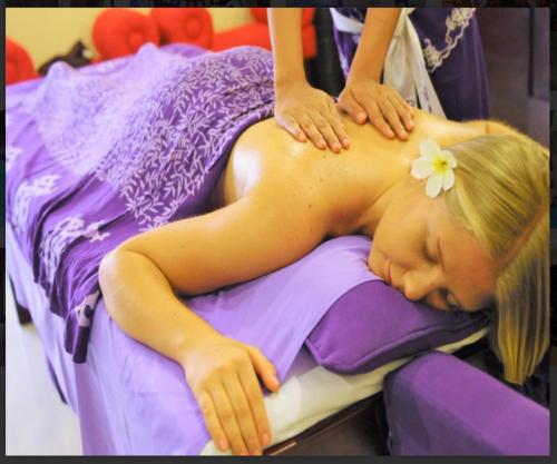 a girl laying on a bed with a flower on her back at Private Pool Classic Villa in Kuta