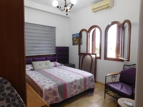 a bedroom with a bed and a chair and windows at Appartement moderne à 5 min de la plage in Cabo Negro
