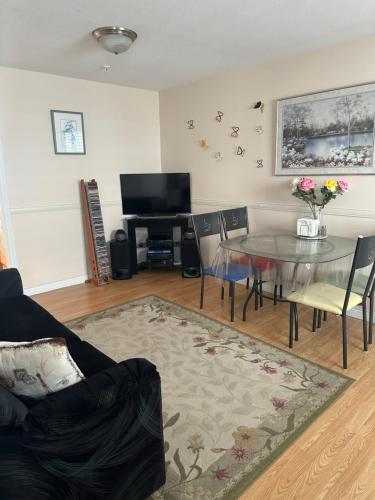 a living room with a table and a television at Clean and Quiet 2 bdr 2 bthr private entrance entire guests suite near Coquitlam Center mall and skytrain in Coquitlam