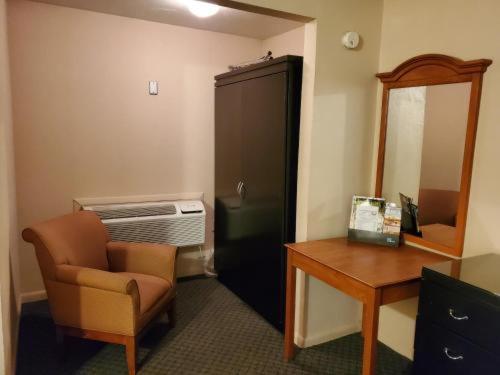Habitación con silla, escritorio y espejo. en Sands Motel en Grants