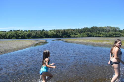 two girls playing in the water on the beach at Coyunche Cabañas y Camping Laja & San Rosendo in Laja