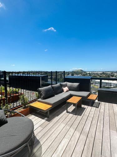 a patio with a couch and tables on a deck at Rooftop Residence in Auckland