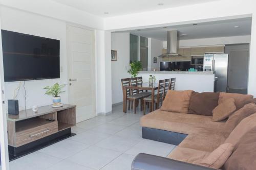 a living room with a brown couch and a kitchen at Amplio Duplex Huanchaco - Vista al Mar y Ascensor in Trujillo