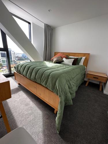 a bedroom with a bed with a green comforter at Rooftop Residence in Auckland