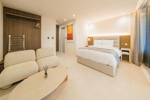 um quarto de hotel com uma cama e um sofá em Haeilri Pool&SPA Hotel em Seogwipo