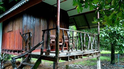 una casa de madera con porche y sillas. en Bamboo House, en Khao Sok