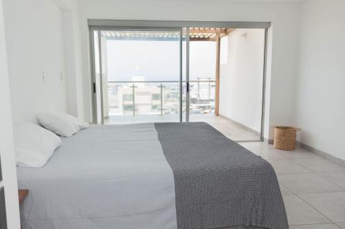 a bedroom with a bed and a large window at Amplio Duplex Huanchaco - Vista al Mar y Ascensor in Trujillo