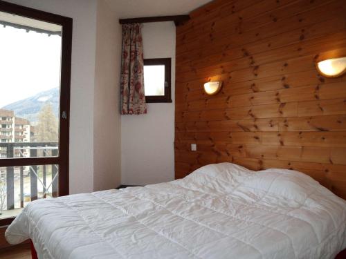 une chambre avec un lit et un mur en bois dans l'établissement Appartement spacieux pour 10 personnes en station, balcons, en face des pistes - FR-1-322-610, aux Orres
