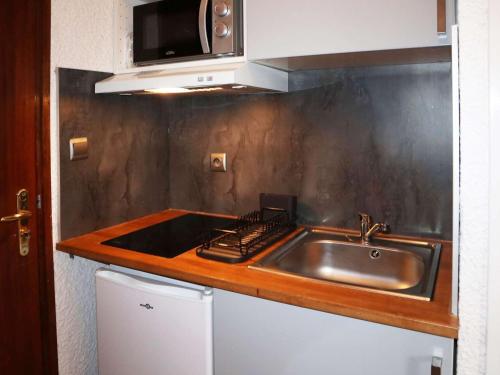 une cuisine avec un évier et un micro-ondes dans l'établissement Charmant studio 2 pers proche pistes - FR-1-322-614, aux Orres