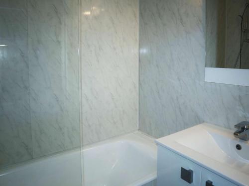 une salle de bain avec une baignoire blanche et un lavabo dans l'établissement Studio cosy pour 4 personnes face aux pistes, balcon sud - FR-1-322-616, aux Orres