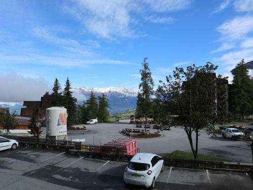 une voiture blanche garée sur un parking avec des montagnes en arrière-plan dans l'établissement Studio 4 pers avec vue sur vallée, animaux admis - FR-1-322-619, aux Orres