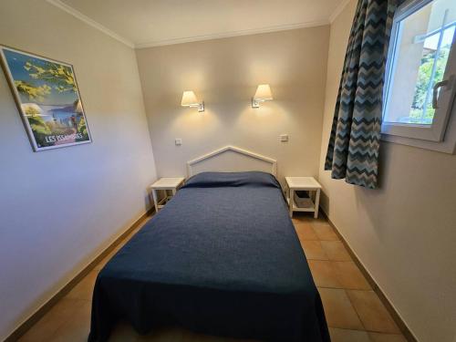 - une petite chambre avec un lit et une couverture bleue dans l'établissement T2 climatisé à 100m de la mer avec piscine et parking - FR-1-768-88, à La Garonnette-Plage
