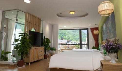 Tropical Paradise Sapa Hotel & Coffee في سابا: غرفة نوم بسرير ابيض وتلفزيون