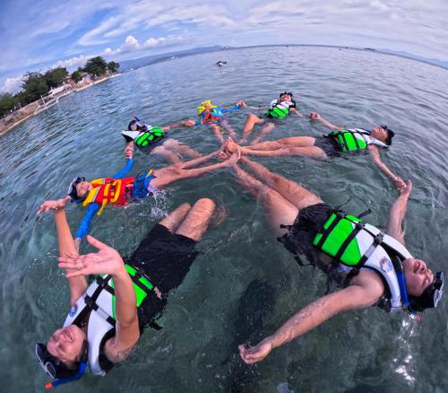 a group of people laying in the water in the water at Byahero's Eskapo Hostel in Moalboal