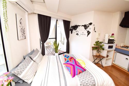 a bedroom with a white bed with colorful pillows at KITAZAWA CS HOUSE / Vacation STAY 76588 in Tokyo
