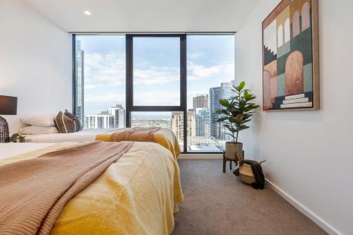 a bedroom with two beds and a large window at VAQUAY Blanc In Southbank in Melbourne