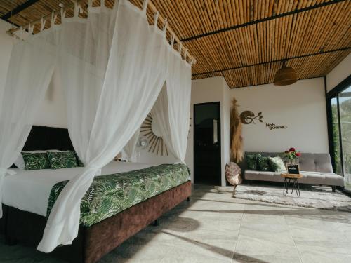 ein Schlafzimmer mit einem Himmelbett und einem Sofa in der Unterkunft NABGUANA in Chinchiná