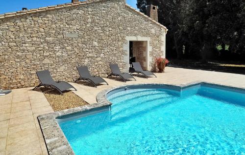 une piscine avec des chaises à côté d'un bâtiment en pierre dans l'établissement Les 3 Filles, à Noves
