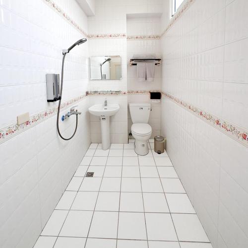 a white bathroom with a toilet and a sink at 虎尾慢遊 in Huwei