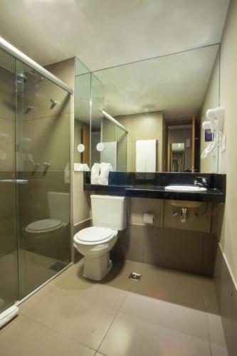 a bathroom with a toilet and a glass shower at BH Raja Hotel in Belo Horizonte