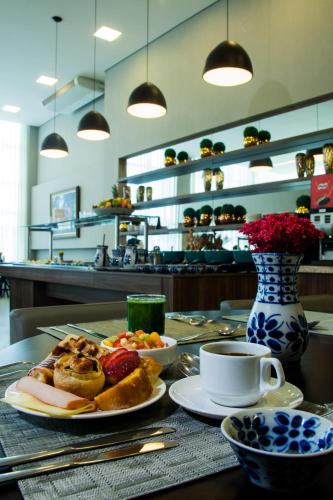 a table with plates of food and a cup of coffee at BH Raja Hotel in Belo Horizonte