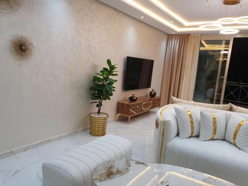 a living room with two white couches and a tv at Le Sélect Appartement in Nador